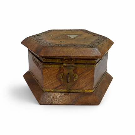 Caja hexagonal de madera oscura con detalles metálicos envejecidos, adorno triangular en la tapa y cierre frontal.