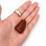 Piedra de jaspe rojo pulida sobre la palma de una mano
