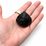 Piedra alargada de turmalina negra sobre la palma de una mano